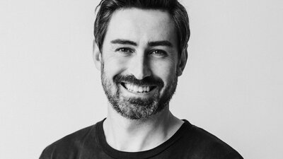 Black and white portrait photo of man smiling wearing tee shirt