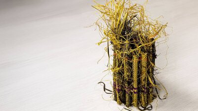 A small sculptural raffia weaving in yellow and black