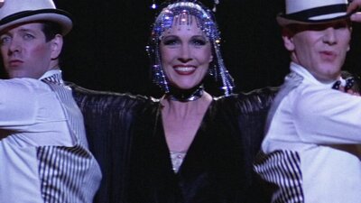 Woman performing with two men on either side wearing white hats