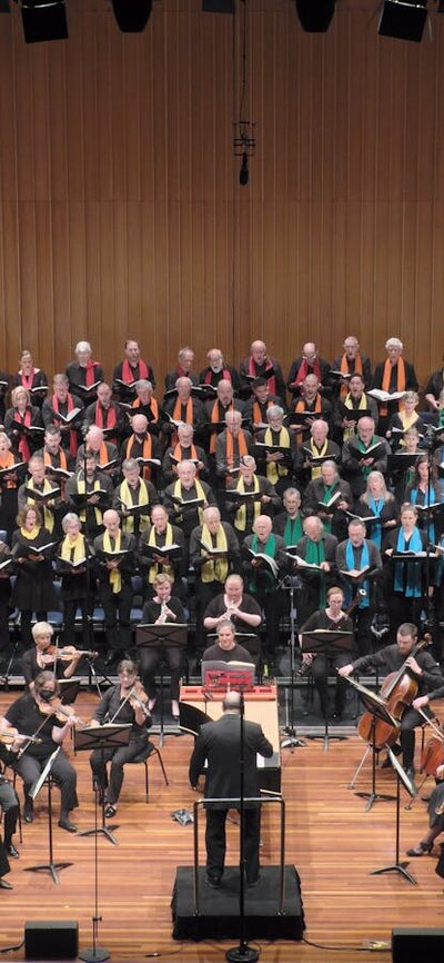 CCS Come and Sing Messiah December 2022 concert Choir, two female and two male soloists, and orchestra on stage conducted by Dr Graeme Morton