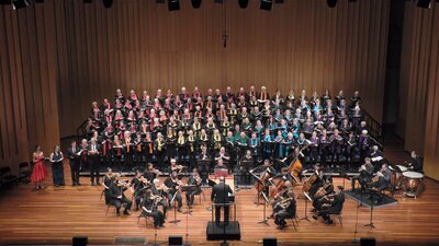 CCS Come and Sing Messiah December 2022 concert Choir, two female and two male soloists, and orchestra on stage conducted by Dr Graeme Morton