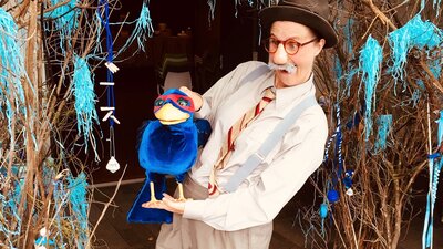 Performer holding a blue bowerbird puppet during a performance.
