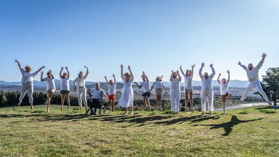 10 people wearing white jumping on top of a hill