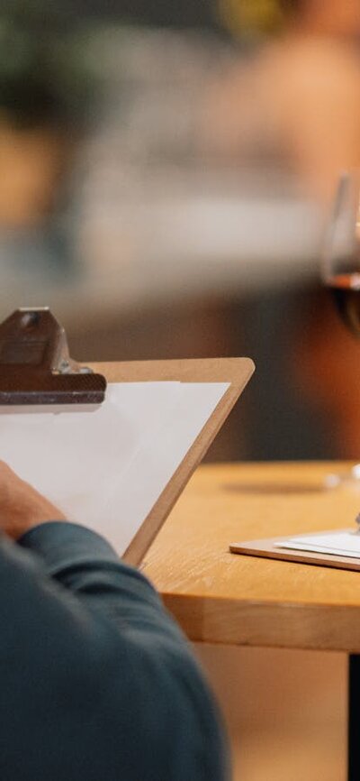 Two people drawing, with a glass of red wine on the table