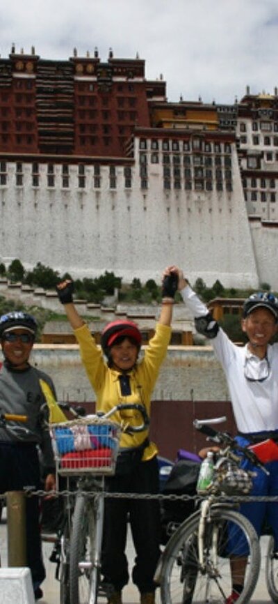 Cyclicsts photographed in front of a building looking happy with arms up in the air