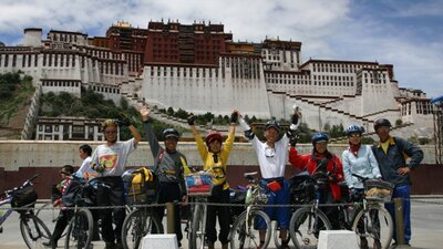 Cyclicsts photographed in front of a building looking happy with arms up in the air
