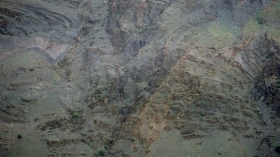 Photo of an epic mountainous background with a tiny cyclist in the distance on a thin road