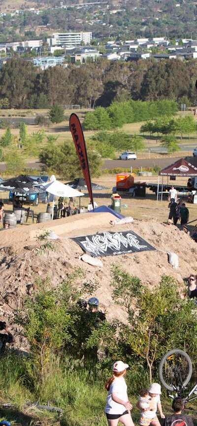 R Willy front flip no hander at Stromlo Forest Park's Hillfire BMX jumps, ACT JAM 2023 R Willy doing a front flip no hander over a big dirt jump as the crowd looks on