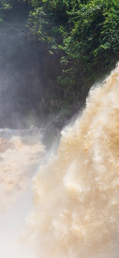 Kayakers under a large waterfall
