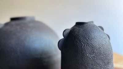 Two round dark coloured vases