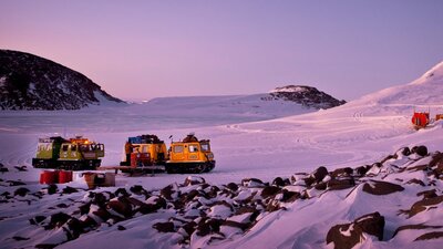 Two Hägglunds in evening light at a field hut near Casey station. © Christopher (Chris) Wilson / AAD Two Hägglunds in evening light at a field hut in a serene snowy landscape.