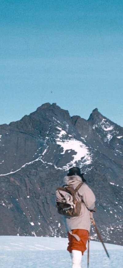 Expeditioners walking towards Mount Henderson, 1960. © George Cresswell/AAD Two hikers trekking across a snow-covered landscape with a mountain in the background.