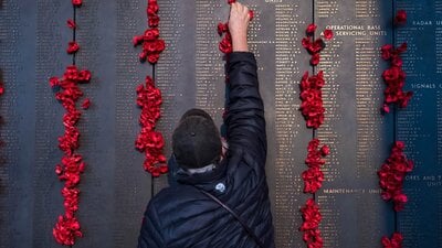 man places poppy on Roll of Honour