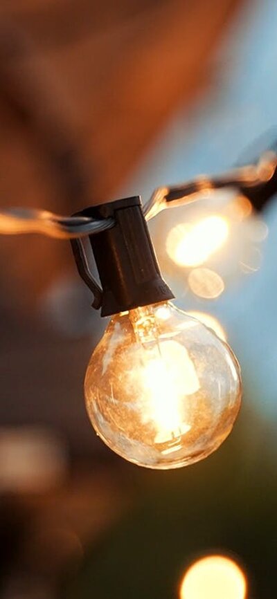 A string of feature festoon lights glow with a warm yellow against a twilight sky