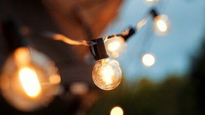 A string of feature festoon lights glow with a warm yellow against a twilight sky