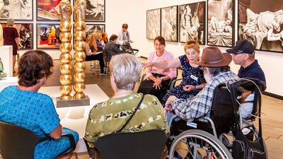 Installation view of Sanné Mestrom, Me & you, 2018 A group of people, some in wheelchairs, sit around a sculpture listening to a guide