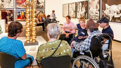 Installation view of Sanné Mestrom, Me & you, 2018 A group of people, some in wheelchairs, sit around a sculpture listening to a guide