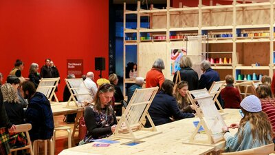Visitors enjoying the Weavers' Studio in Arthur Boyd: Tapestries, National Gallery of Australia People sitting at a table weaving