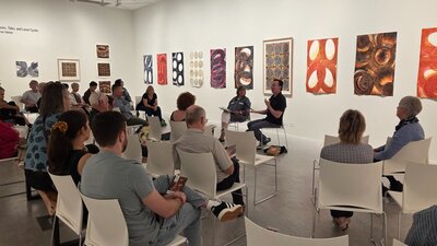 An Artists in Conversation event at Belco Arts A small crowd of people, seated in a gallery, listen as two artists have a discussion.