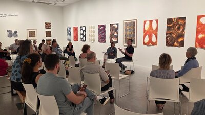 An artist discusses his work in a gallery featuring abstract paintings.