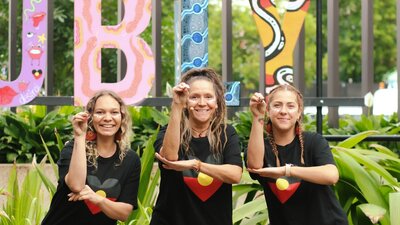 Aunty Sharron and the Daughts Three First Nations Australian women making emu shapes with their arms.