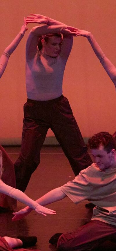 A group of dancers performing a synchronized contemporary piece, with warm lighting.