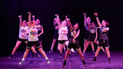 A group of young dancers performing a synchronized routine, wearing basketball inspired costumes.