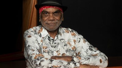 Warren H Williams smiling at camera with a red bandana and black hat