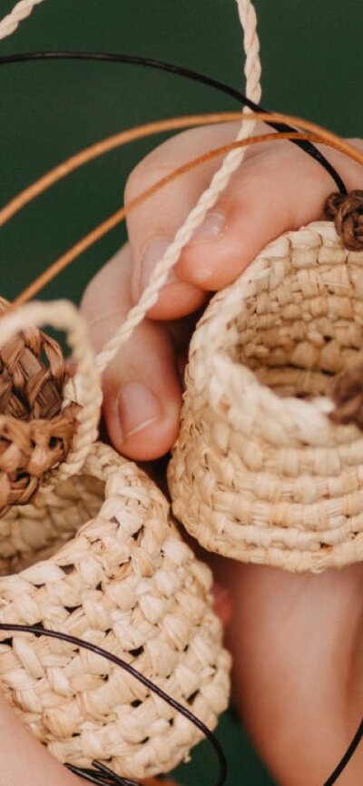 Hands holding small weaving objects