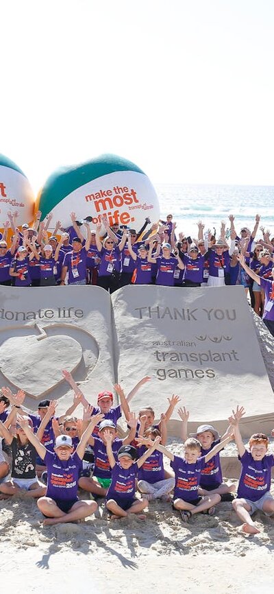 Australian Transplant Games attendees around a sand sculpture that reads "thank you - donatelife"