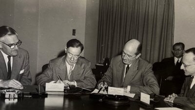 A sepia photograph of four gentlemen writing.