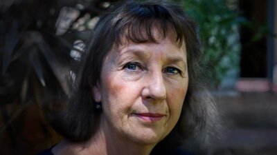 A close up image of a woman with long dark hair and a fringe