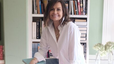 A woman sitting on a stool with a bookcase behind her