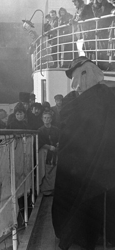 The Elephant Man, Friday 14 March Figure standing with white cover on his head, many people surrounding the figure and watching