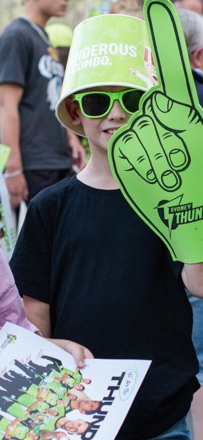 Young fans pose for a photo with Sydney Thunder giveaways at Manuka Oval