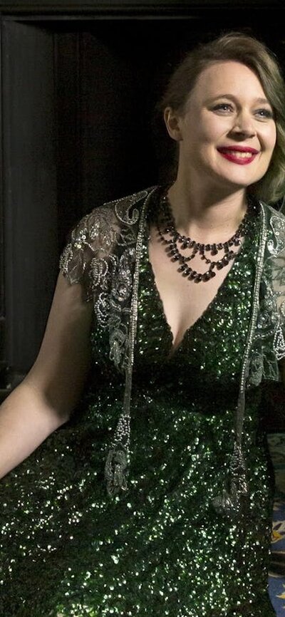 A double bass player seated n the floor in an elegant green dress.