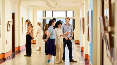 A group of people standing in a gallery looking at pictures on the walls