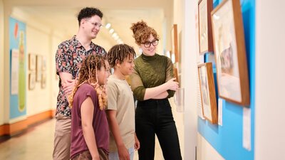 Two children and two adults standing together looking at a picture on the wall