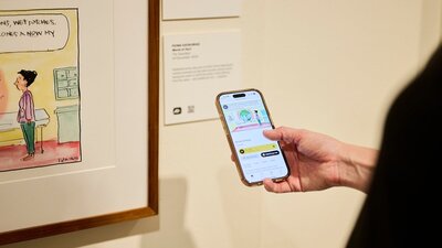 Phone shows audio description of political cartoon in gallery.