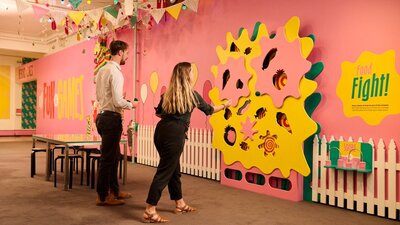 people looking at colourful wall display at Behind the lines exhibition