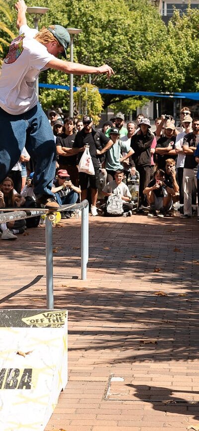 Skateboarder performs Backside Lipslide in front of crowd at Belconnen