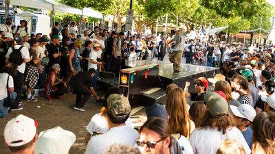 Skateboarder performs nose manual in front of crowd in Canberra city