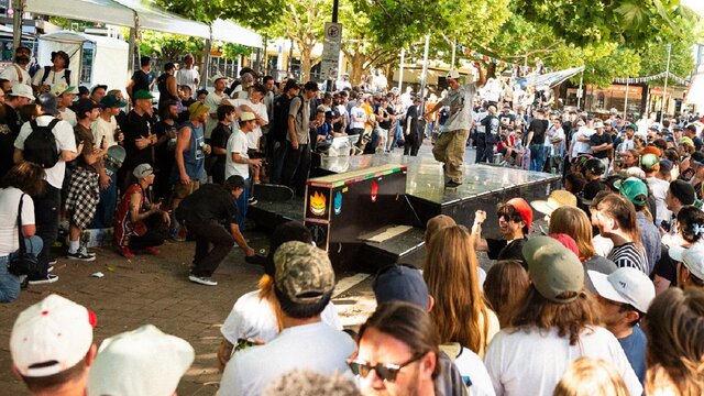 Skateboarder performs nose manual in front of crowd in Canberra city