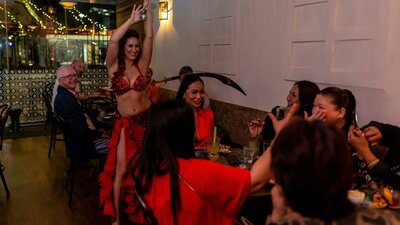 Belly dancer performing at Bar Beirut. She is balancing a sword on a seated customer's head.