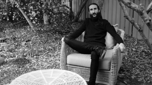 Photo of the artist, Benedict Moleta A man sitting in a wicker chair in the garden