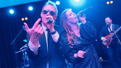 A man and a woman singing into microphones on a stage.