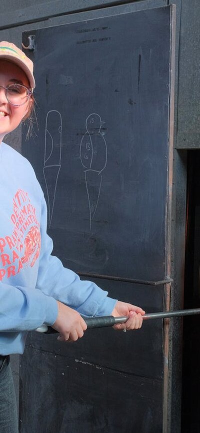 Participant in the Glassworks hotshop working with molten glass