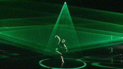 The BOLD Festival A dancer on stage with triangles of bright green light spotlighting
