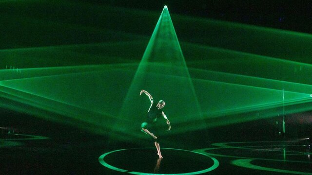 The BOLD Festival A dancer on stage with triangles of bright green light spotlighting