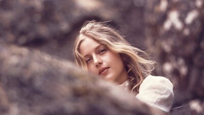 Woman looking at camera, slightly hidden behind tree